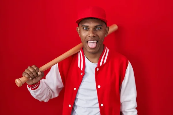 面白い表情で楽しそうに舌を突き出して野球をしている若いヒスパニック系の男 感情の概念 — ストック写真