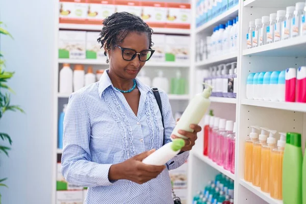 中年非洲裔美国妇女顾客在药店拿着洗发水瓶 — 图库照片