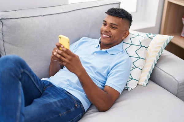 Young Latin Man Using Smartphone Lying Sofa Home — Foto Stock