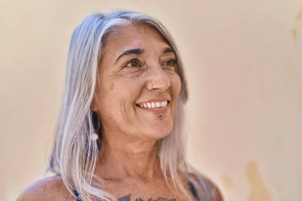 Middle age grey-haired woman smiling confident looking to the side over isolated white background