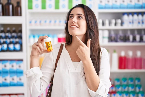 Joven Morena Comprando Farmacia Sosteniendo Pastillas Cara Seria Pensando Pregunta — Foto de Stock