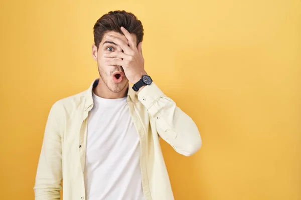 Young Hispanic Man Standing Yellow Background Peeking Shock Covering Face — Stock Fotó