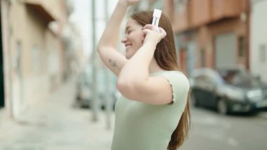 Young beautiful woman listening to music and dancing at street