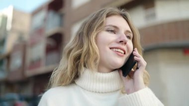 Genç sarışın kadın gülümsüyor. Kendine güveni tam. Akıllı telefondan konuşuyor.