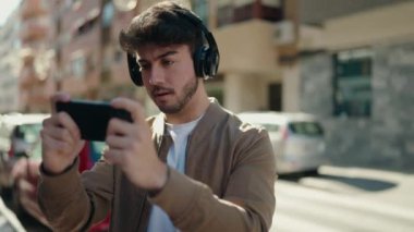 Genç İspanyol adam caddede video oyunu oynamaya konsantre oluyor.