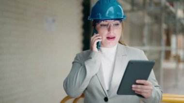 Akıllı telefondan konuşan genç bir mimar. Sokakta dokunmatik ped kullanıyor.