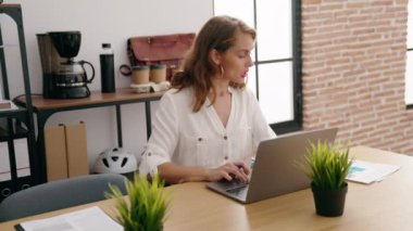 Young beautiful hispanic woman business worker using laptop reading document at office