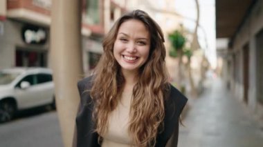 Young hispanic woman smiling confident doing ok sign with thumb up at street