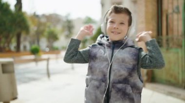Blond child smiling confident listening to music and dancing at street