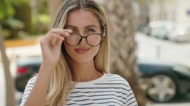 Sokakta kendinden emin gülümseyen genç sarışın kadın.