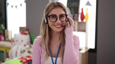 Young blonde woman teacher smiling confident having video call at kindergarten
