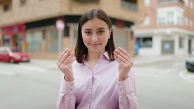 Young hispanic woman smiling confident doing spend money gesture at street