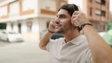 Sokakta müzik dinlerken kendinden emin gülümseyen İspanyol genç adam.