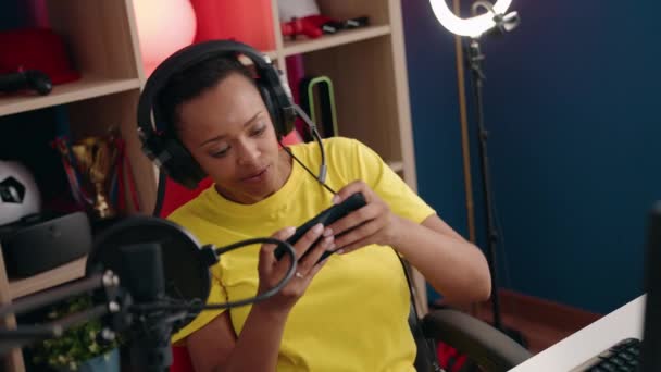 アフリカ系アメリカ人の女性がゲームルームでスマートフォンを使ってビデオゲームをするストリーマー — ストック動画