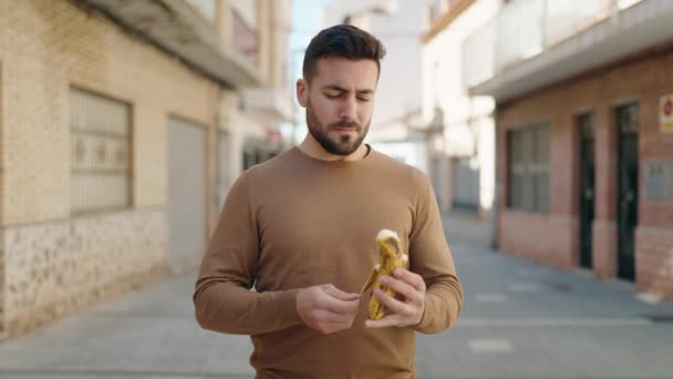 Νεαρός Ισπανόφωνος Χαλαρή Έκφραση Τρώει Μπανάνα Στο Δρόμο — Αρχείο Βίντεο
