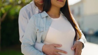 Young latin couple smiling confident touching belly standing at street