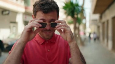 Young hispanic man smiling confident wearing sunglasses at street