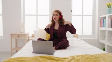 Genç ve güzel İspanyol kadın dans ediyor ve yatak odasında oturmuş müzik dinliyor.