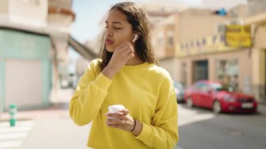 Genç Afro-Amerikalı kadın gülerek sokakta müzik dinliyor.
