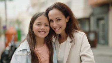 Mother and daughter smiling confident doing heart symbol with hands at street