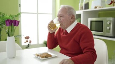 Son sınıf öğrencisi evde kurabiye yiyip meyve suyu içiyor.