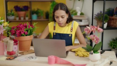 Young african american woman florist smiling confident using laptop at flower shop