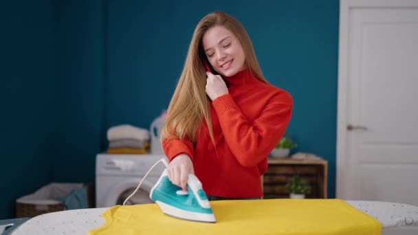 Νεαρή Ξανθιά Γυναίκα Μιλάει Στο Smartphone Σιδέρωμα Ρούχα Στο Πλυσταριό — Αρχείο Βίντεο