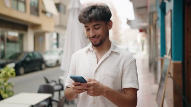 年轻的阿拉伯男子在街上用智能手机充满自信地微笑 — 图库视频影像