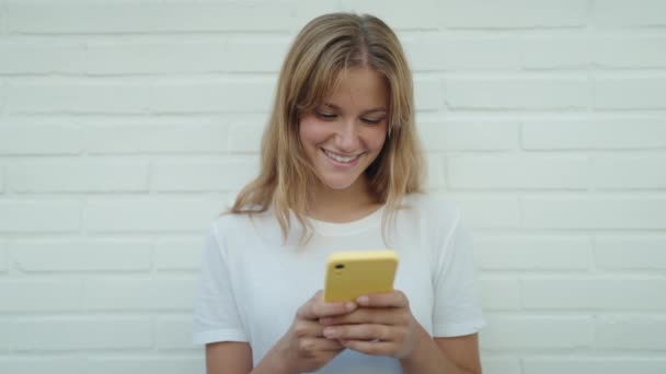 Jovem Loira Sorrindo Confiante Usando Smartphone Sobre Isolado Fundo Tijolo — Vídeo de Stock
