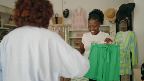 アフリカ系アメリカ人女性ショップアシスタントと顧客購入スカートで衣料品店 — ストック動画