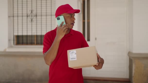 Jonge Latijnse Man Levering Werknemer Holding Pakket Praten Smartphone Straat — Stockvideo
