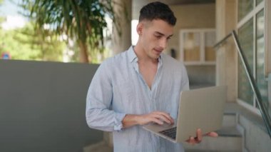 Sokağın ortasında dizüstü bilgisayar kullanan genç bir İspanyol.