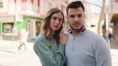 Genç çift gülümsüyor. Birbirlerine sarılıyorlar. Sokakta duruyorlar.