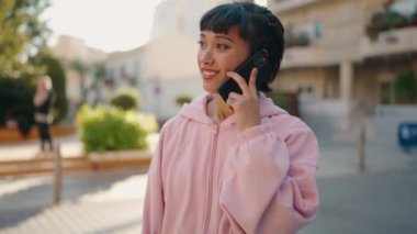 Genç İspanyol kadın gülümsüyor. Kendine güveniyor. Akıllı telefondan konuşuyor.