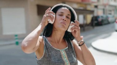 Orta yaşlı İspanyol kadın müzik dinliyor ve sokakta dans ediyor.