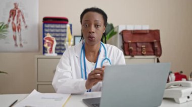 Afrikalı Amerikalı kadın doktor klinikte ilaç yazıyor.