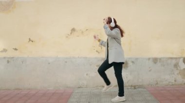 Sokak ortasında müzik dinleyip dans eden orta yaşlı bir işletme yöneticisi.