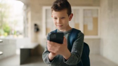 Okulda akıllı telefon kullanan sarışın bir çocuk.