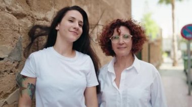 İki kadın anne ve kızı sokakta öpüşürken gülümsüyor.