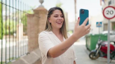 Young hispanic woman smiling confident having video call at street