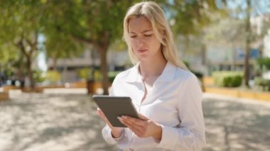 Parkta dokunmatik ped kullanan genç sarışın kadın.