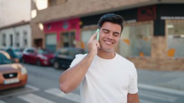 Genç İspanyol adam gülümsüyor. Kendine güveniyor. Sokakta akıllı telefondan konuşuyor.