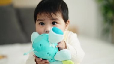 Sevimli İspanyol bebek. Yatak odasında oturmuş fil bebeği emiyor.