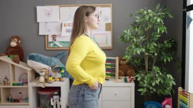 Young blonde woman preschool teacher smiling confident standing at kindergarten