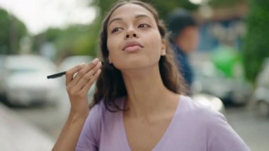 Genç Afrikalı Amerikalı kadın gülümsüyor. Caddedeki akıllı telefondan kendine güvenen sesli mesaj dinliyor.