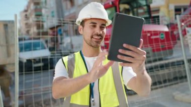 Young hispanic man architect having video call at street