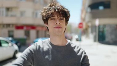 Young hispanic man smiling confident doing photo gesture with hands at street