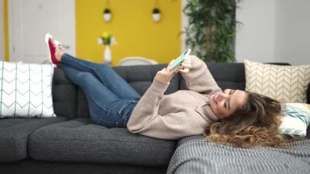 Junge Schöne Hispanische Frau Mit Smartphone Hause Auf Sofa Liegend — Stockvideo