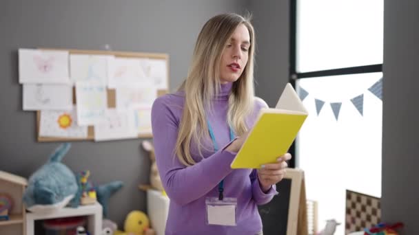 Young Blonde Woman Preschool Teacher Reading Book Kindergarten — Stockvideo