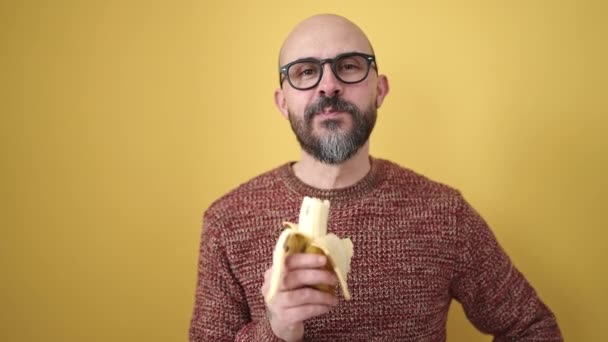 Jeune Homme Chauve Souriant Confiant Manger Banane Sur Fond Jaune — Video